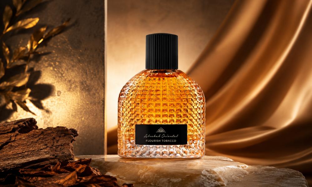 Alrehab Oriental Flourish Tobacco perfume bottle in a luxurious warm amber setting with tobacco leaves, wood, and golden satin.