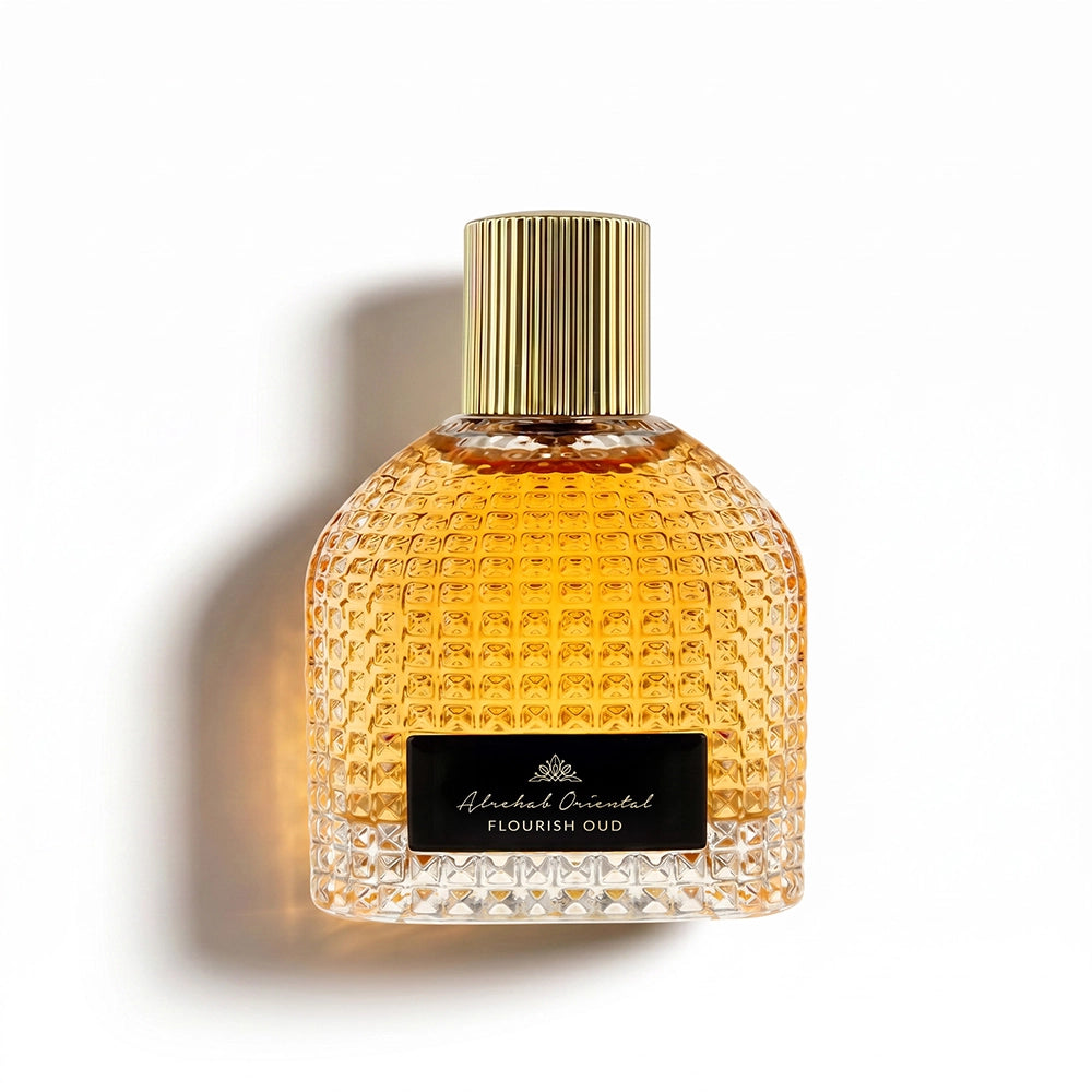 A textured glass perfume bottle filled with amber liquid, featuring a ribbed gold cap and a black label with white text reading 'Michael Malul Flourish Oud'. The bottle is photographed on a clean white background with a soft shadow to the left.