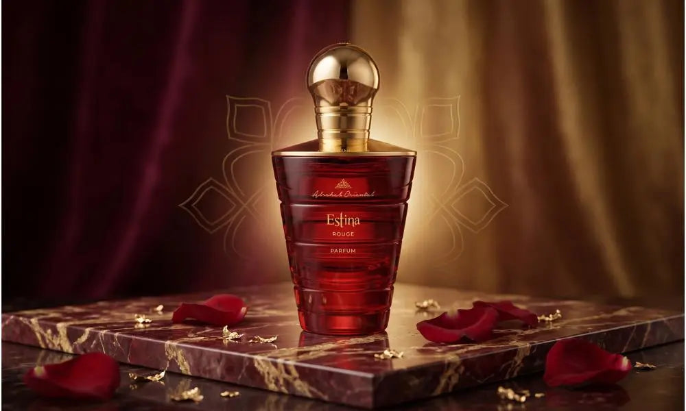 A luxurious red Estina Rouge perfume bottle with a golden cap, placed on a marble surface surrounded by elegant red rose petals.