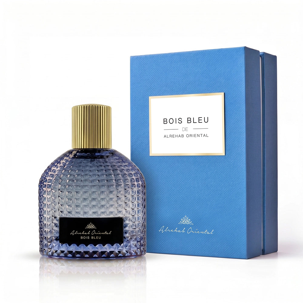 A bottle of Bois Bleu by Al Rehah Oriental perfume with a textured blue glass body and gold cap, displayed next to its blue box packaging on a white background.
