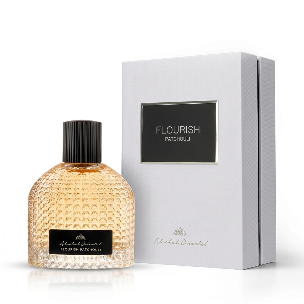 A bottle of Alhalal Oriental Flavourish Patchouli perfume with a textured amber glass body and black cap, shown next to its white presentation box with a black label.