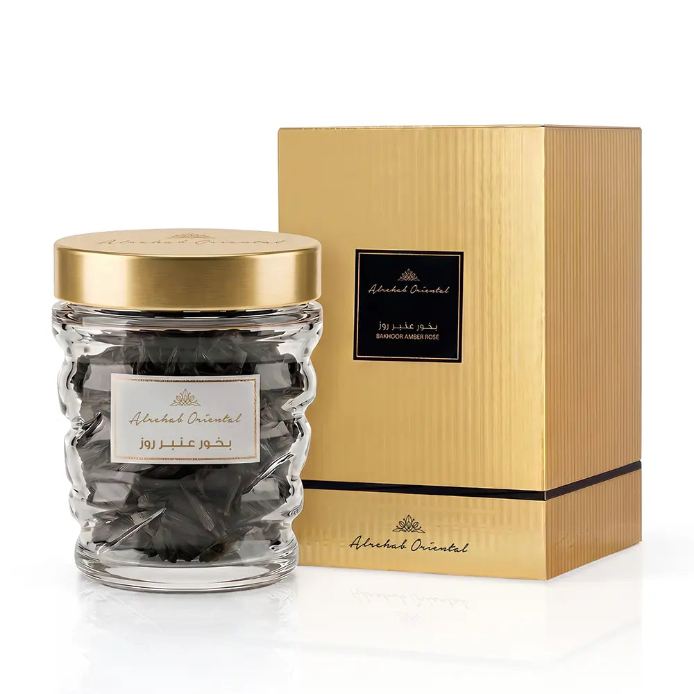 A clear glass jar filled with dark chocolate pieces and topped with a gold lid, shown beside a tall gold gift box. The labels read Abdulrahman Oriented.